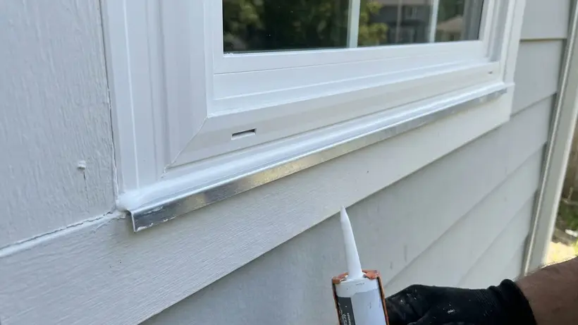 Close up of properly flashed and caulked window frame installation on a house.